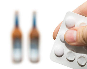 таблетки на фоне бутылок с алкоголем