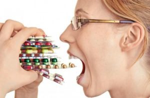 женщина суёт себе в рот пачки таблеток
